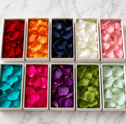 Ten boxes of rose petals in assorted colors including red, orange, navy, white, pink, teal, magenta, purple, green, and mint on marble surface